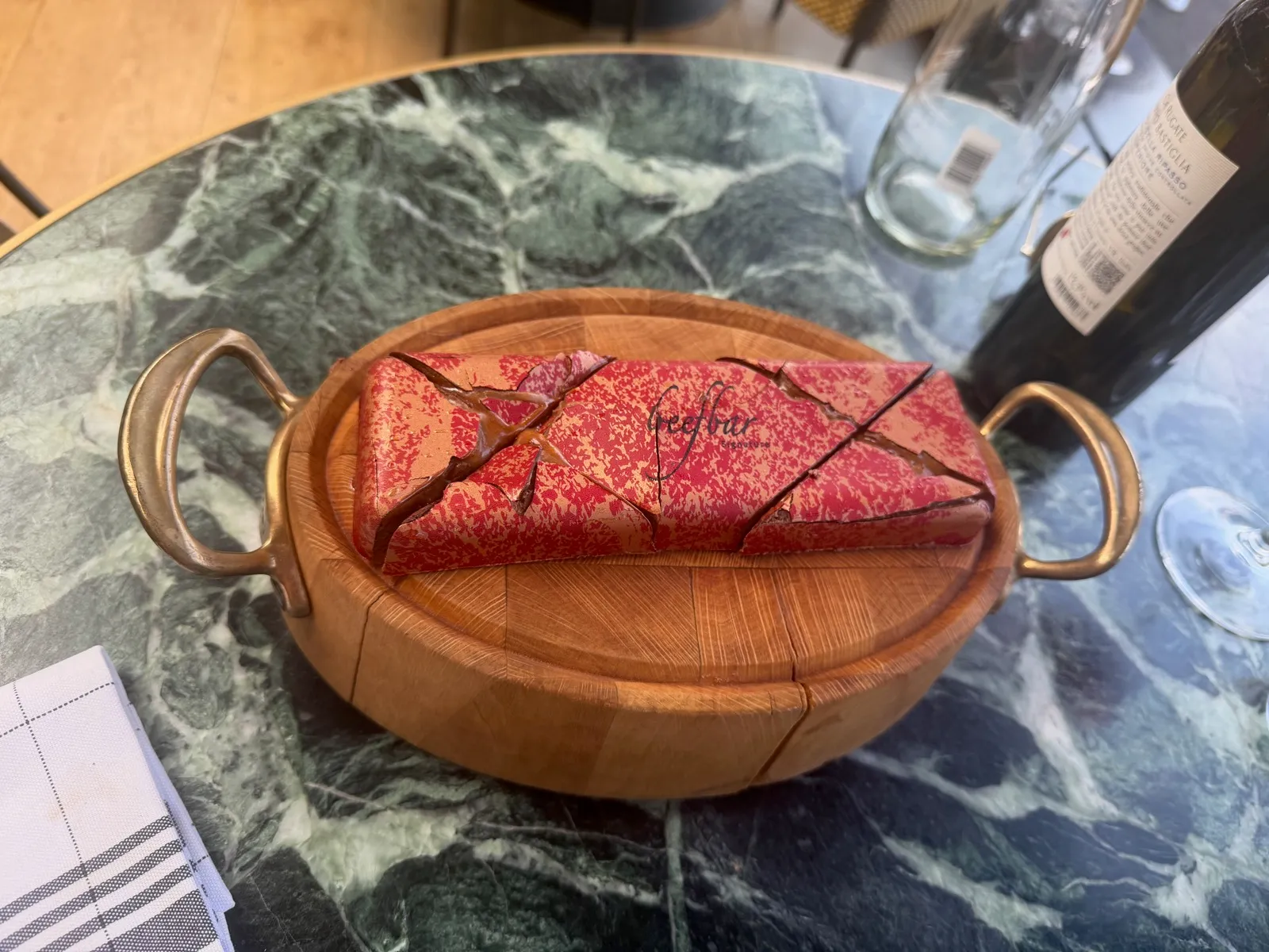 The Beefbar marble chocolate bar at Beefbar Monte-Carlo, looking like a joint of marbled beef with the Beefbar signature across it, on a round wooden board with brass handles