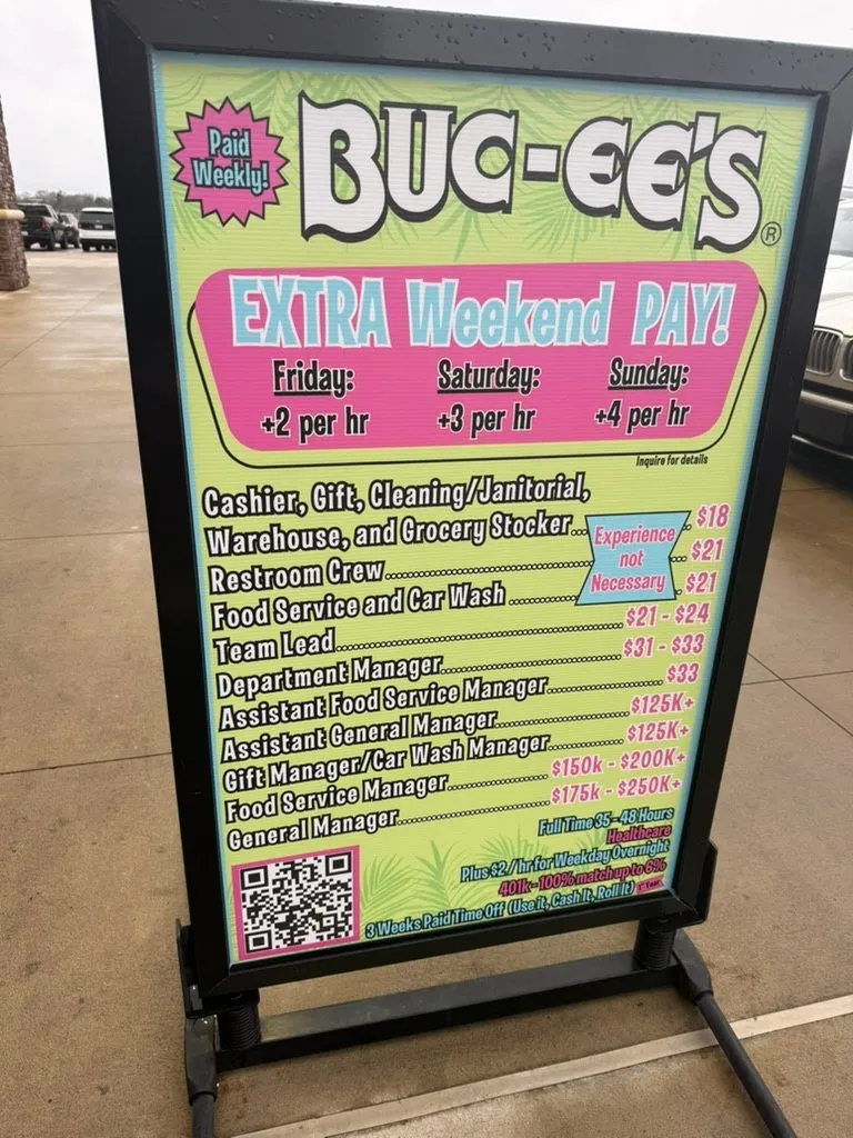 A Buc-ee's recruitment board in a car park listing hourly rates by role, with EXTRA Weekend PAY at the top offering an extra $2 on Friday, $3 on Saturday and $4 on Sunday
