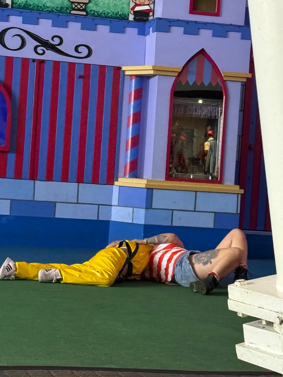 A couple lying on the floor of the pavilion next to the funfair at Butlins Skegness late in the evening