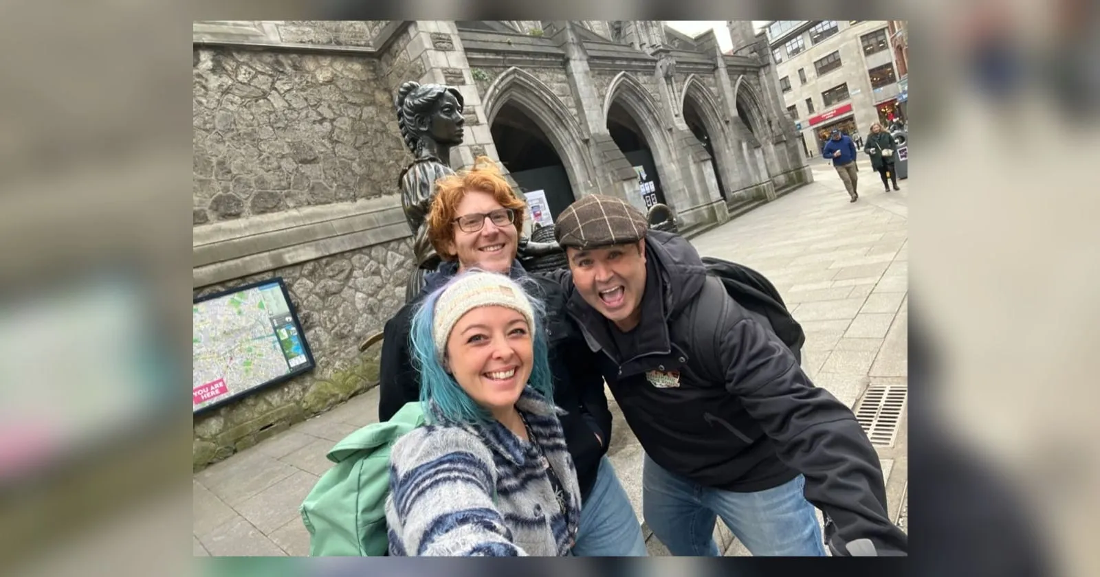 The three of us squashed into a selfie by the Molly Malone statue in Dublin, Kevin grinning in a flat cap on the right