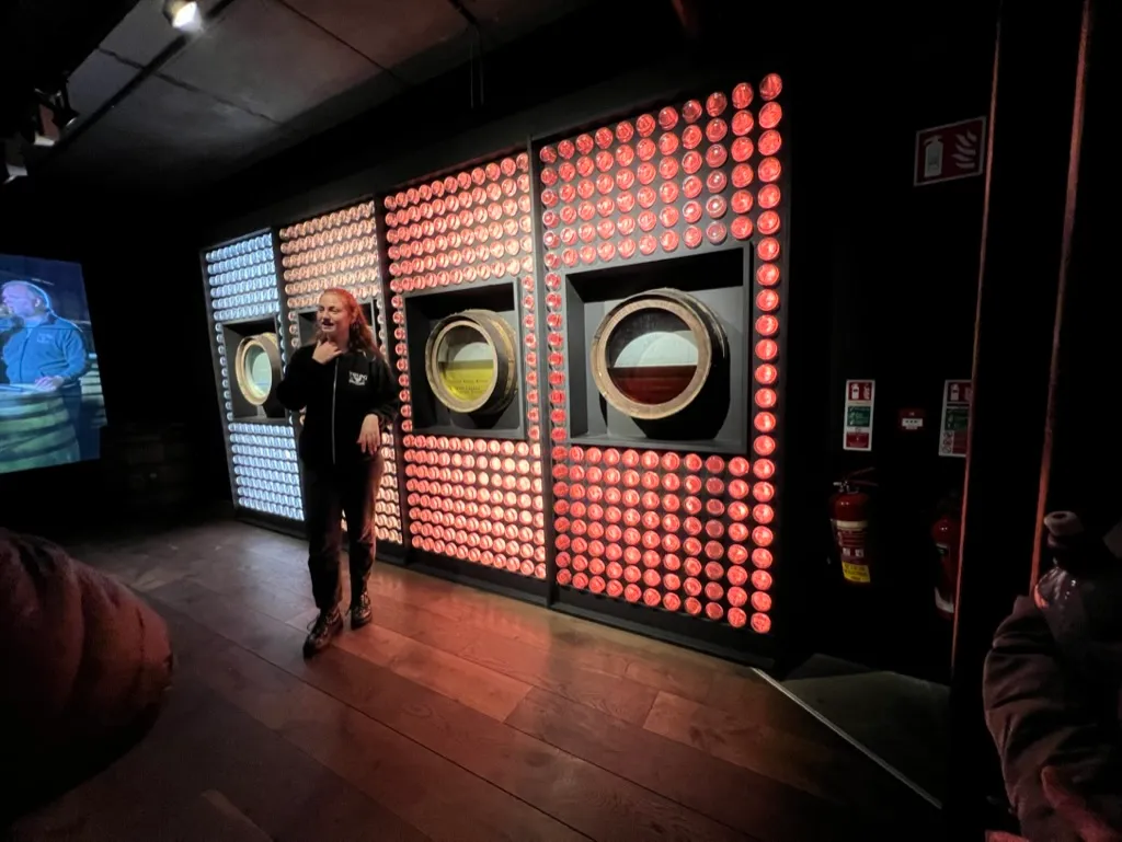 A guide standing in front of the backlit wall of cask ends in the Teeling tasting room, three barrel ends set into it
