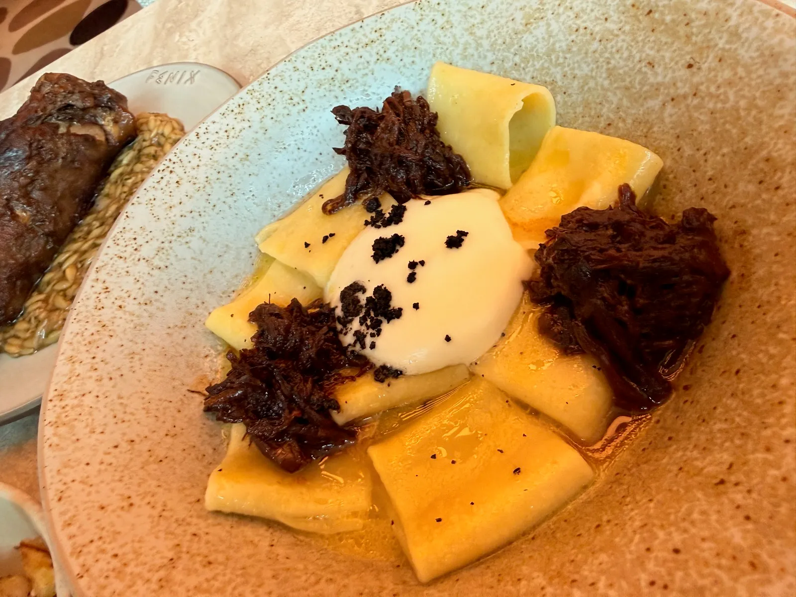 Beef Paccheri at Fenix Manchester, wide flat pasta tubes with shredded braised beef, a quenelle of white sauce and a scattering of dark crumb.
