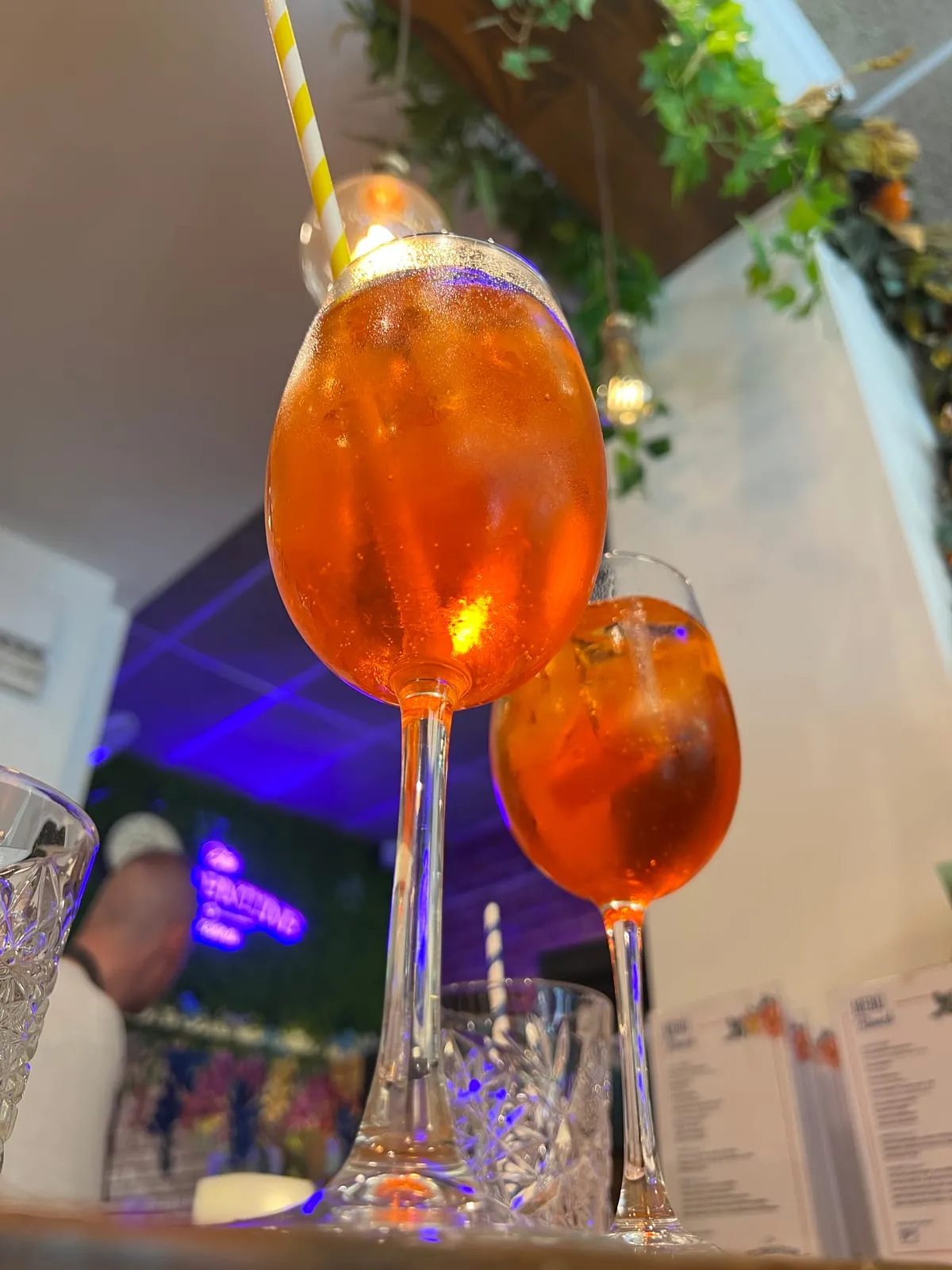 Two Aperol Spritzes on the bar at The Florentine, Barcelona, with the neon sign and the brunch menus behind them