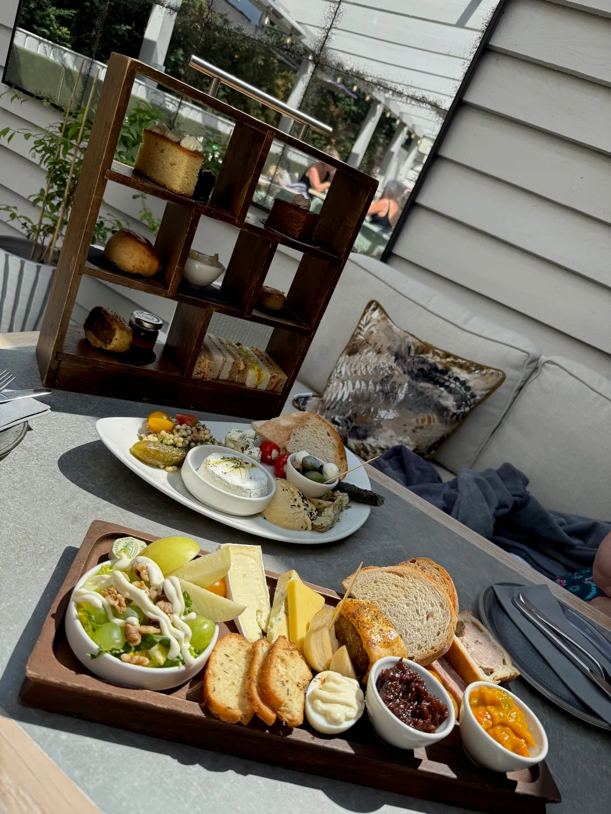 The afternoon tea stand, the mezze plate and the ploughman's board together on the table outside, with the pool loungers behind