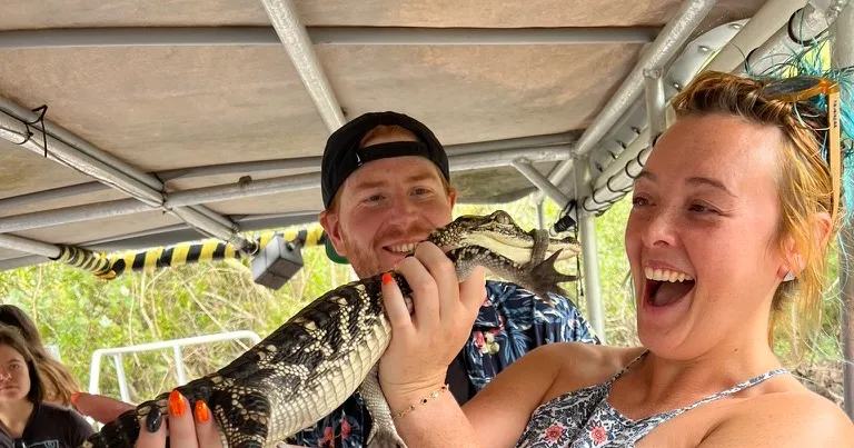 The two of us on the swamp boat, laughing, holding a baby alligator up between us