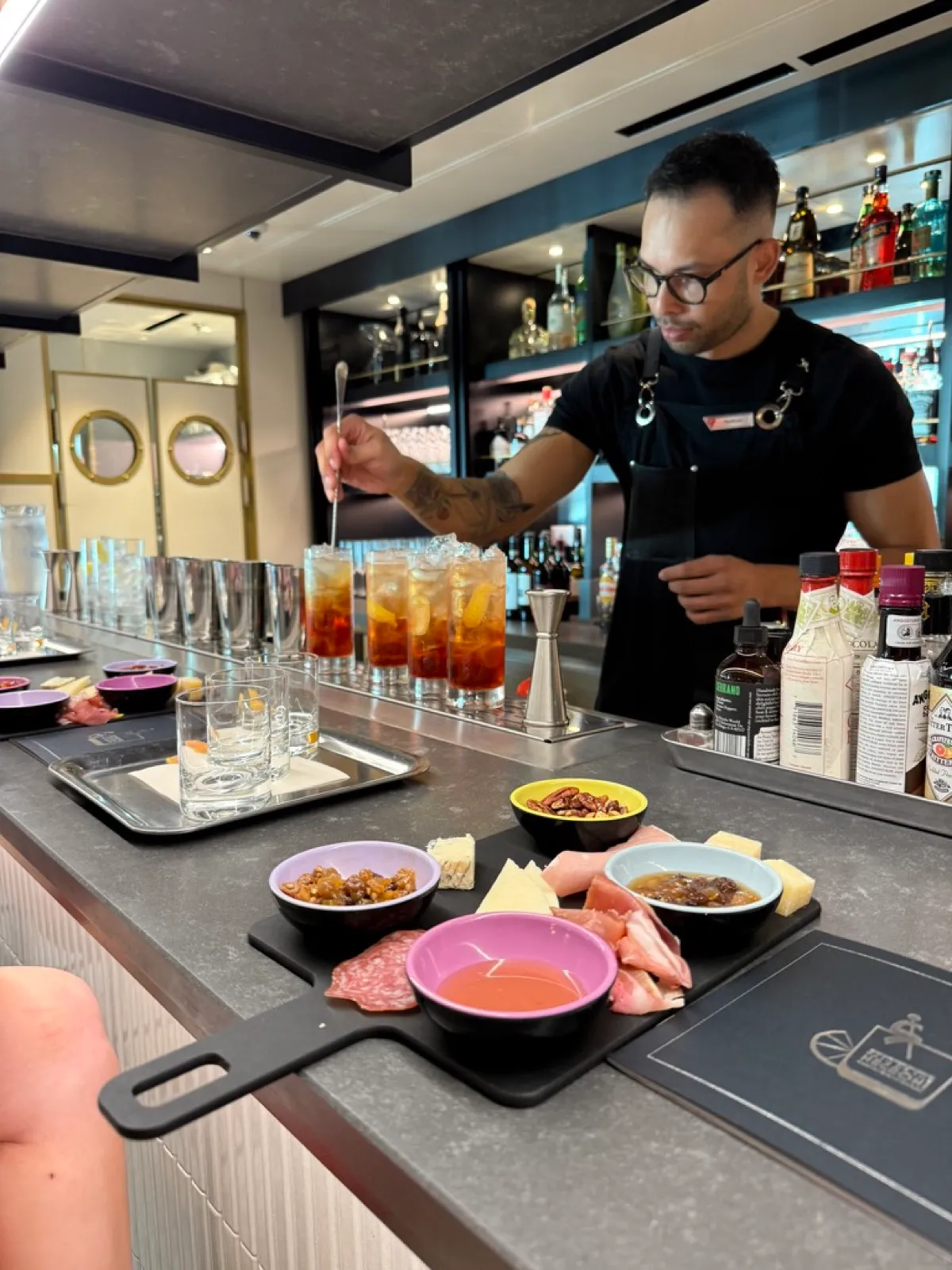 The cocktail master stirring a row of Negronis behind the bar on Virgin Voyages