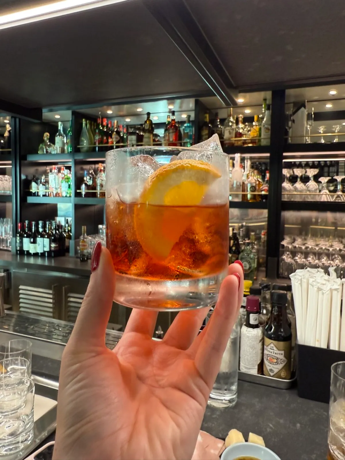 A classic Negroni with an orange slice, held up at the bar on Virgin Voyages