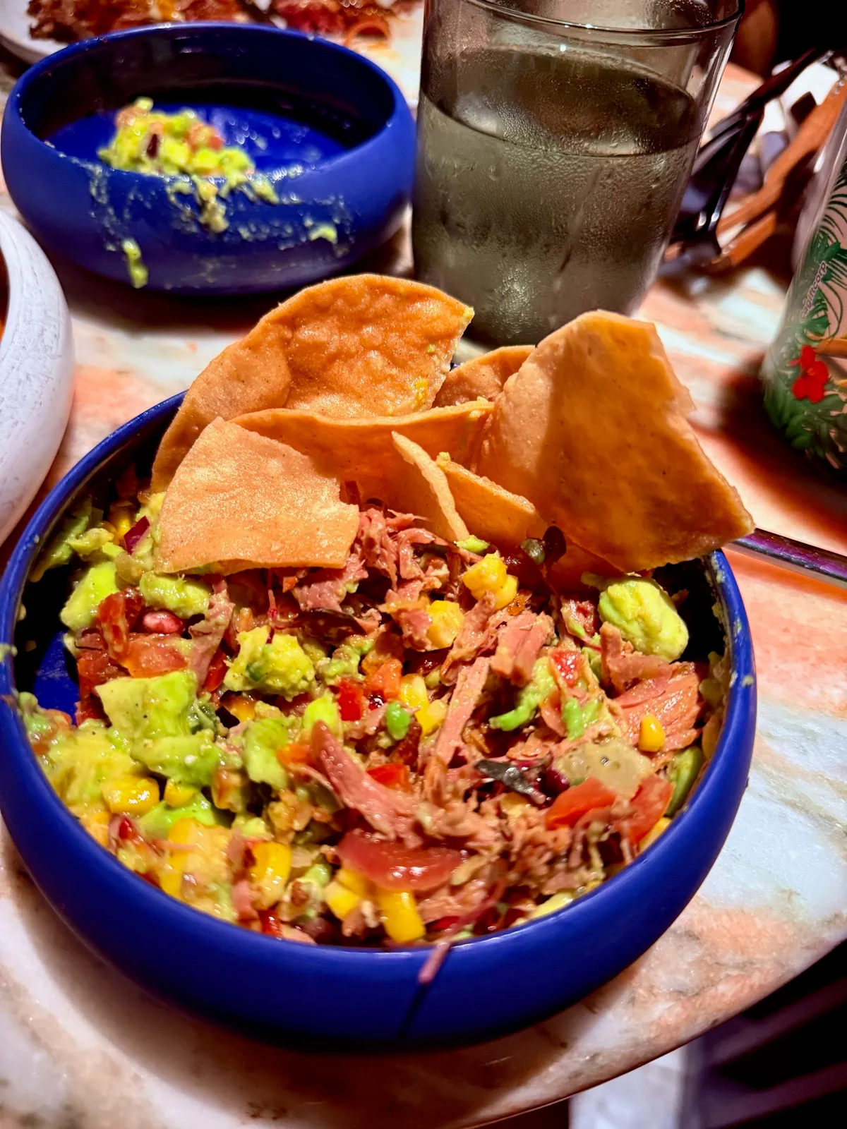 A bowl of mega chips and dip from Pink Agave on Virgin Voyages, loaded with esquites corn, guacamole and pulled meat