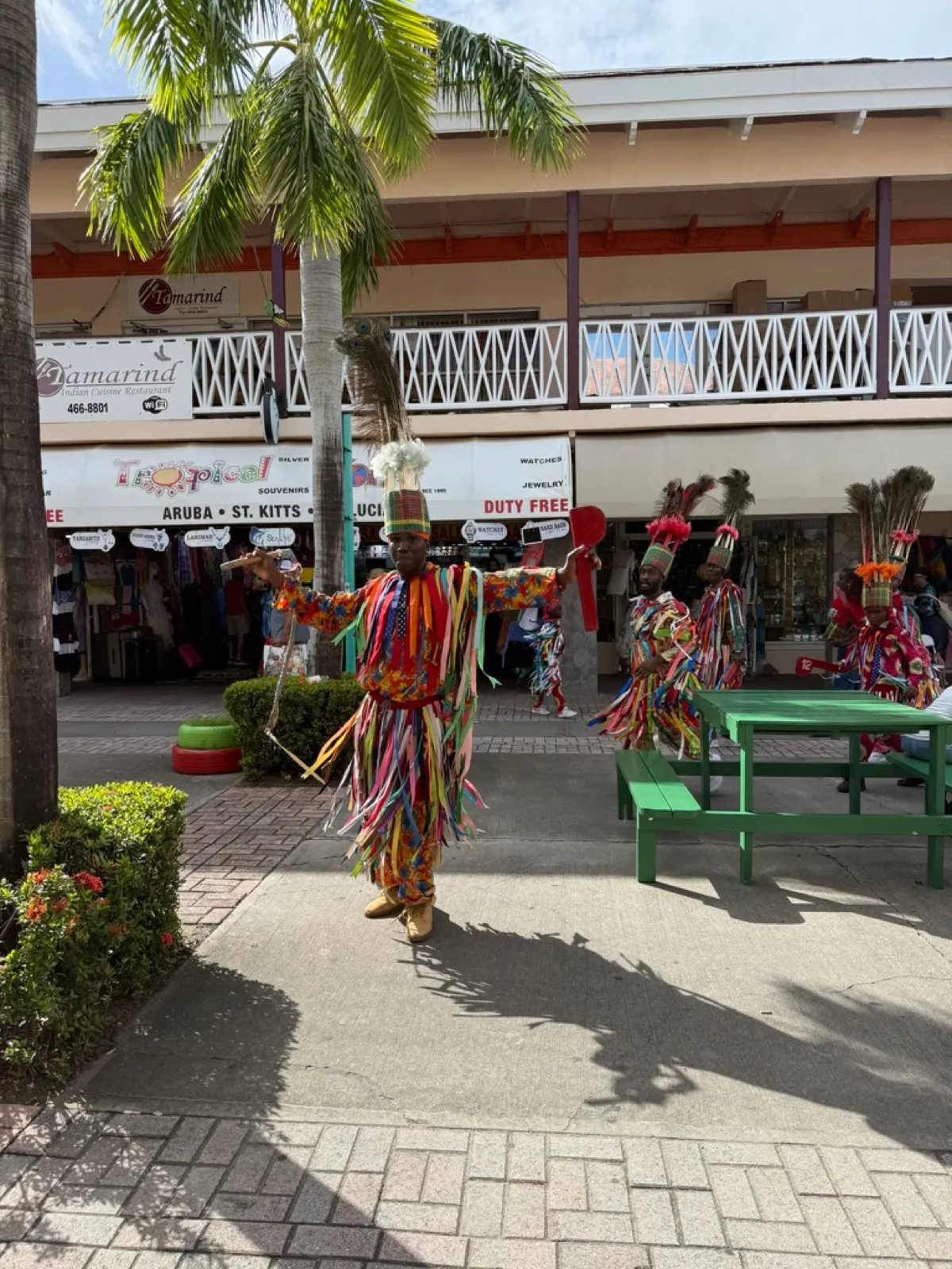 Masquerade dancers in brightly coloured ribbon costumes and feathered headdresses performing outside the duty free shops in Basseterre, St Kitts