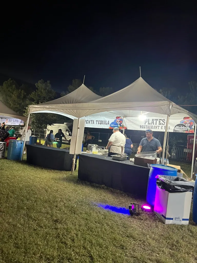 The Plates Restaurant and Bar and Penta Tequila tents, chefs serving from trays under a white marquee at night