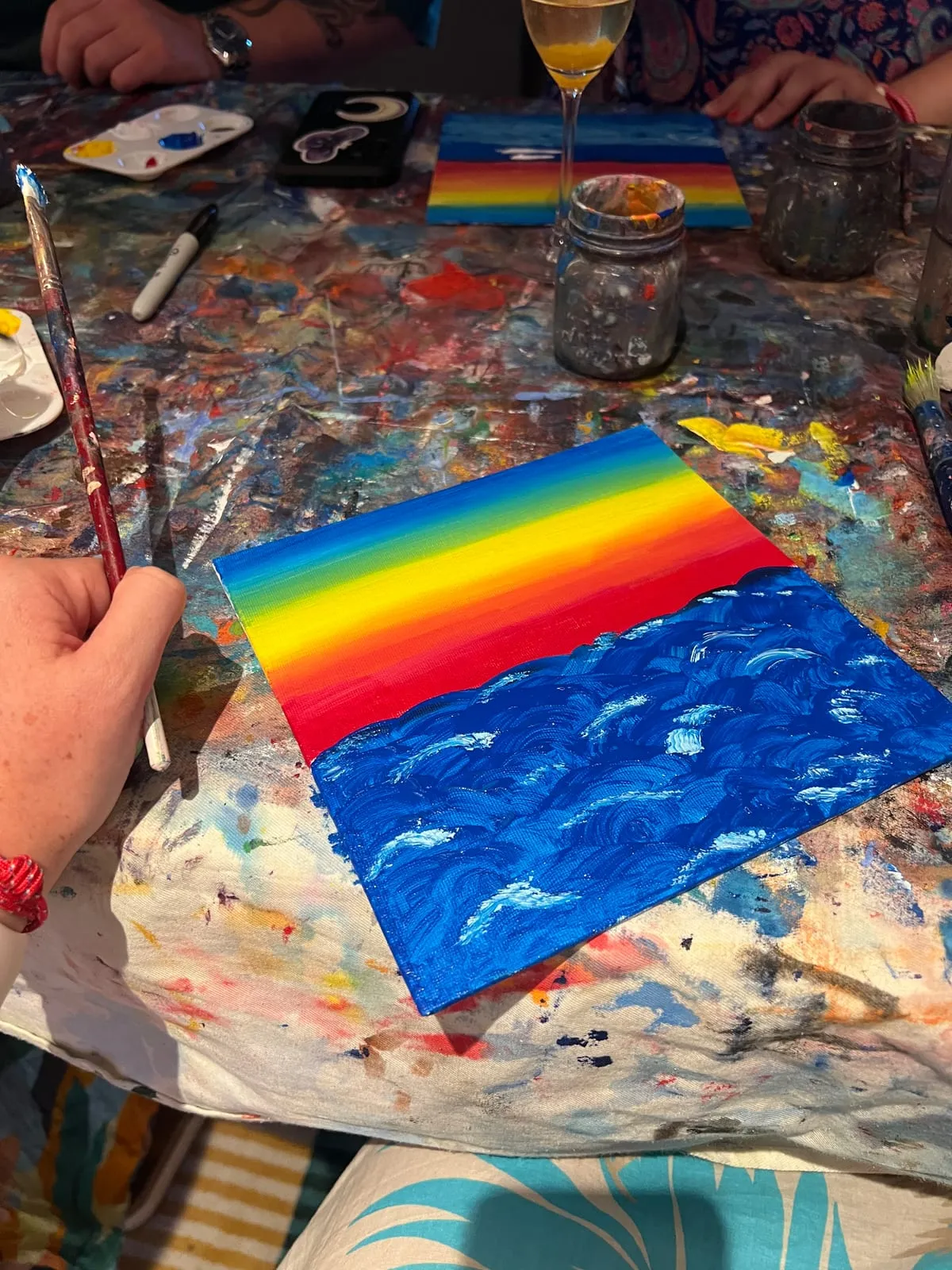 The same canvas a few steps later, the red stripe now part of a full rainbow sky above a thickly swirled blue sea