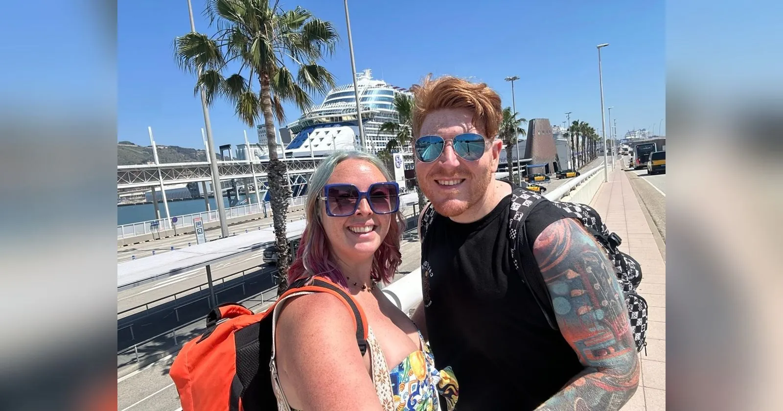 Sofi and Alex in sunglasses on the walkway to the cruise terminal in Barcelona, palm trees and a large cruise ship behind them under a clear blue sky