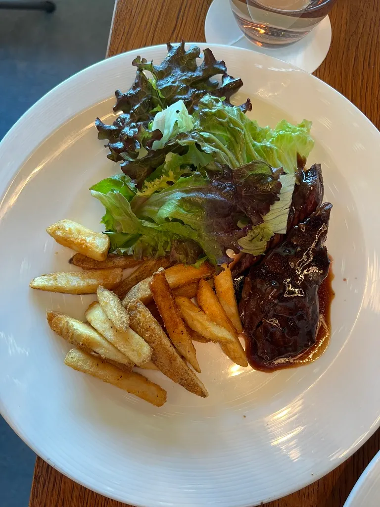 The Hanger Steak at The Wake: sliced steak under a dark glossy glaze, with thick cut chips and a pile of red and green salad leaves.
