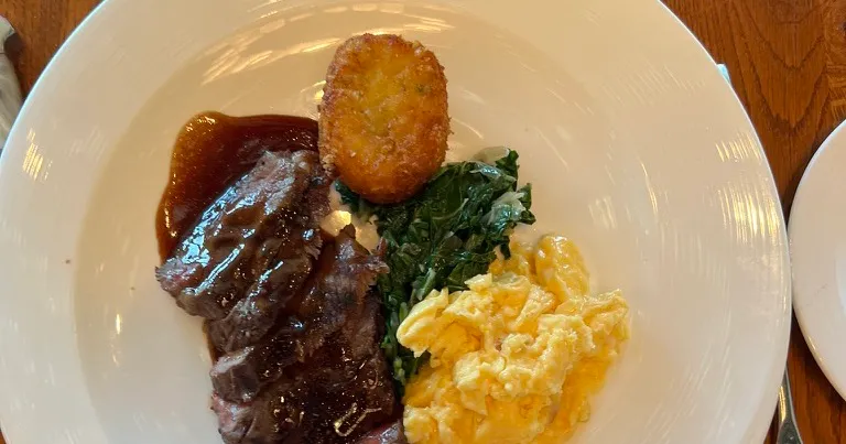 The Steak and Eggs at The Wake: sliced steak in gravy with a hash brown, wilted greens and scrambled eggs