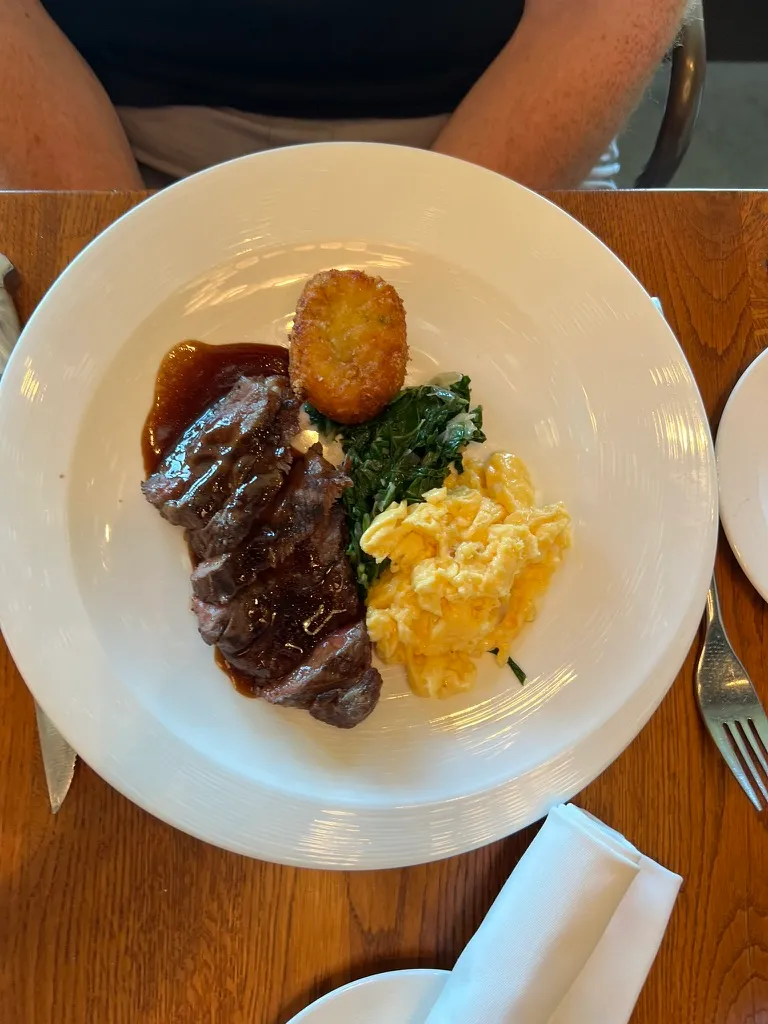 The Steak and Eggs at The Wake: sliced steak in gravy with a crisp hash brown, wilted greens and a pile of scrambled eggs.