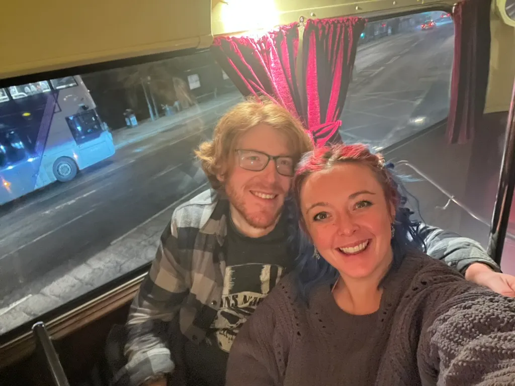 The two of us squeezed into a seat on the top deck of the ghost bus, pink velvet curtains beside us and another bus going past the window in the dark