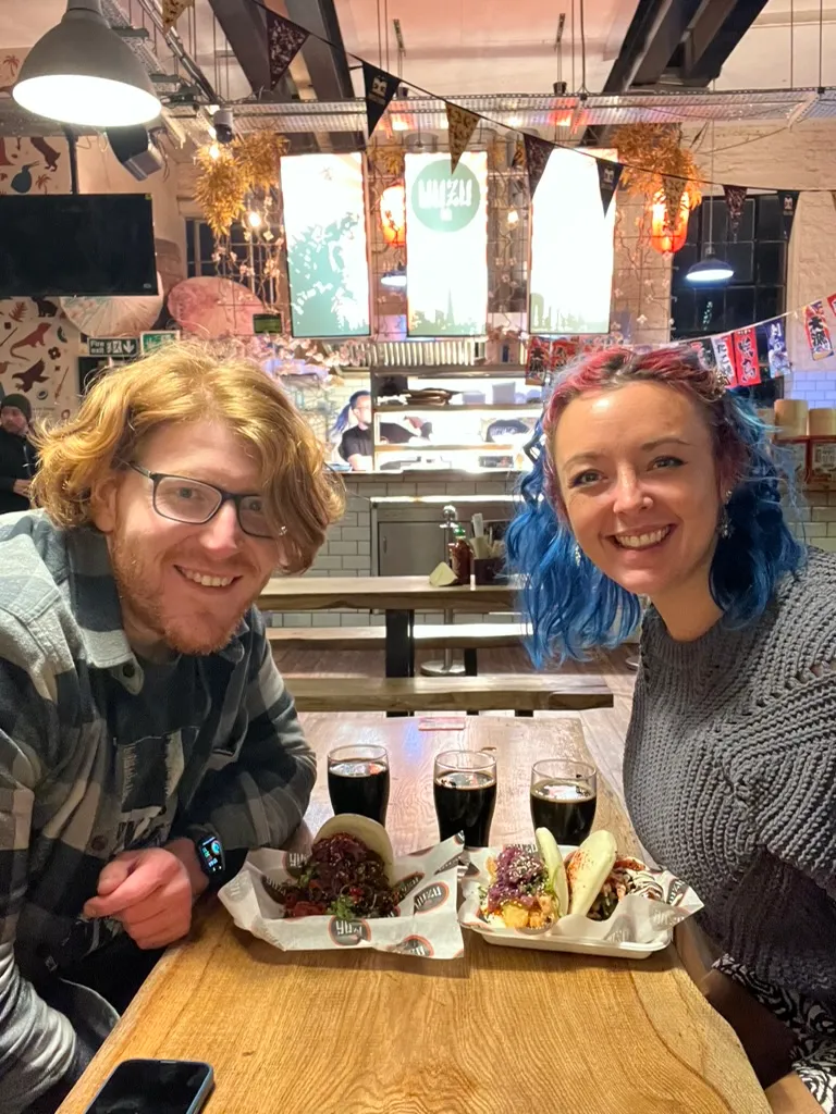 The two of us at a long wooden table in Brew York with three glasses of beer between us and two paper trays of bao buns
